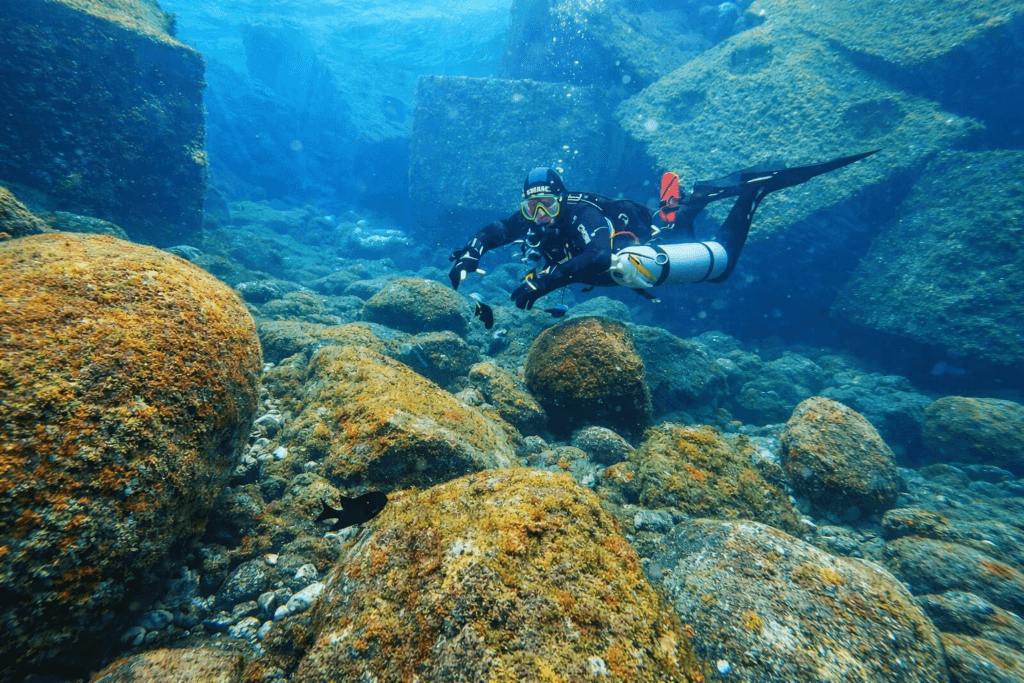 Taucher in Sidemount-Konfiguration mit seitlich getragenen Flaschen