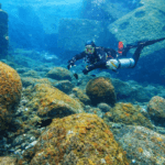 Taucher in Sidemount-Konfiguration mit seitlich getragenen Flaschen